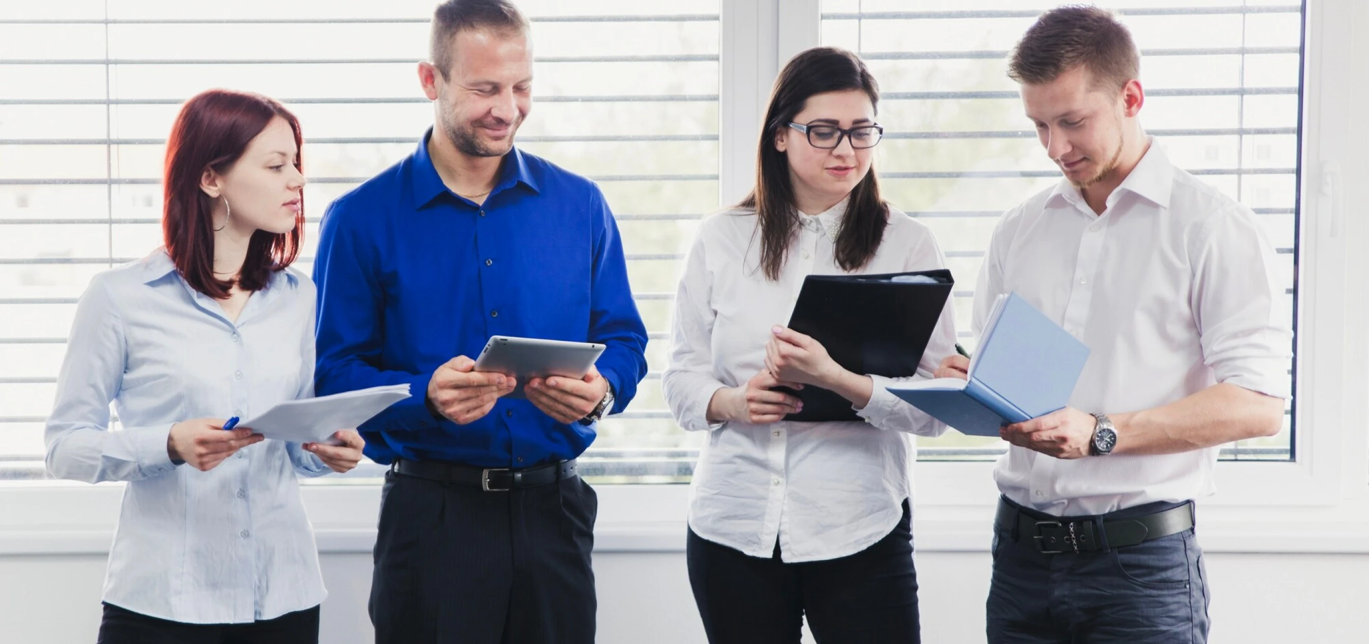 Equipe de três profissionais analisando informações em um tablet